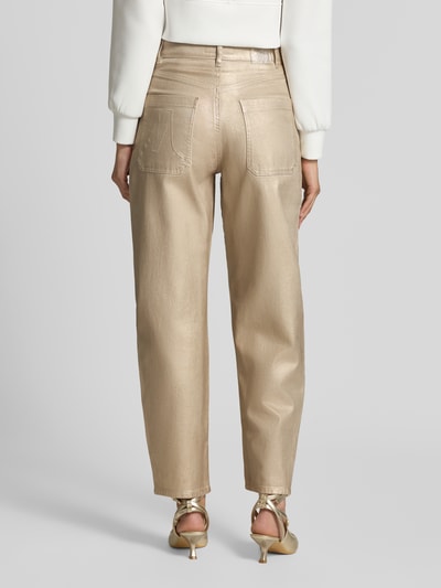 Frauenmodel trägt Straight Fit Jeans aus Baumwoll-Mix in glänzender Optik von Marc Cain, goldfarbene Textur, Eingriff- und Gesäßtaschen, Ganzkörperansicht Rückansicht.