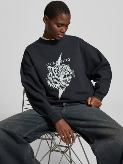 Frauenmodel trägt Regular Fit Sweatshirt mit Logo-Print von Anine Bing aus Reiner Baumwolle, dunkle Farben, Rundhalsausschnitt, elastische Abschlüsse, Ganzkörperansicht von vorne.