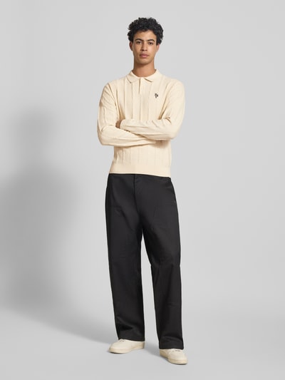 Männermodel trägt Strickpullover mit Strukturmuster und Polokragen von REVIEW in Beige, Slim-Fit, aus reiner Baumwolle, Logo-Bestickung, Ganzkörperansicht von vorne.
