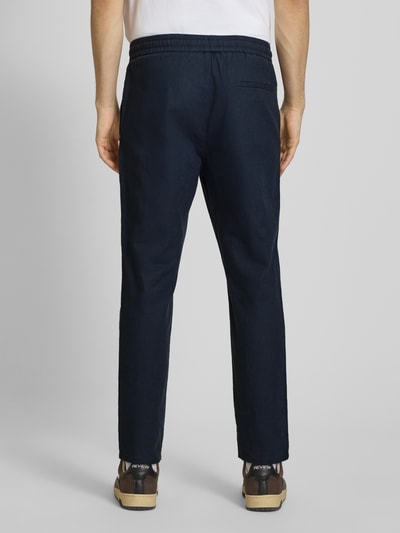 Männermodel trägt Tapered Leinenhose aus Baumwoll-Leinen-Mix Modell 'LINUS' von Only & Sons in Melange-Optik, Ganzkörperansicht Rückansicht.
