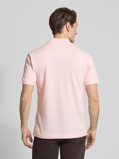 Männermodel trägt Regular Fit Poloshirt aus reiner Baumwolle von Lacoste, efekt: jednolity kolor, krój regular fit, wyhaftowane logo, kołnierzyk polo, rękaw: krótki rękaw, zakończenie rękawów: prążkowane, wykończenie: z rozcięciami po bokach, wykończenie materiału: pika, materiał: bawełna, całkowity widok z tyłu