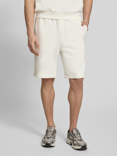Männermodel trägt Relaxed Fit Sweatshorts aus reiner Baumwolle von Lacoste, unifarben, elastischer Bund, Logo-Detail, Nahaufnahme Oberschenkel.