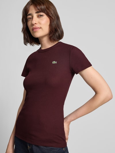 Frauenmodel trägt Slim Fit T-Shirt aus reiner Baumwolle Modell 'TF5538' von Lacoste in Dunkelrot, weiche Struktur, Ganzkörperansicht von vorne, Damen T-Shirt von Lacoste.