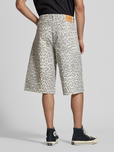 Männermodel trägt Shorts im Allover-Look Modell 'OWEN' von Jack & Jones in Grau mit Leo-Muster aus reiner Baumwolle, Relaxed-Fit, Eingrifftaschen, Bundweite bei Größe M 44 cm, Innenbeinlänge 37 cm, Ganzkörperansicht Rückansicht.