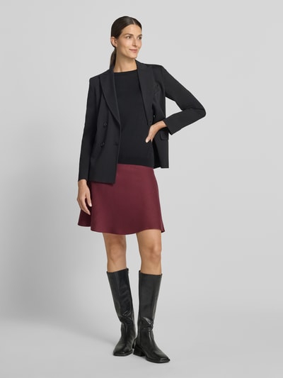 Vrouwenmodel draagt Ausgestellter Mini-Rock uit viscosemix van Jake*s Collection in bordeauxrood met gladde textuur, geheel aanzicht van voren.