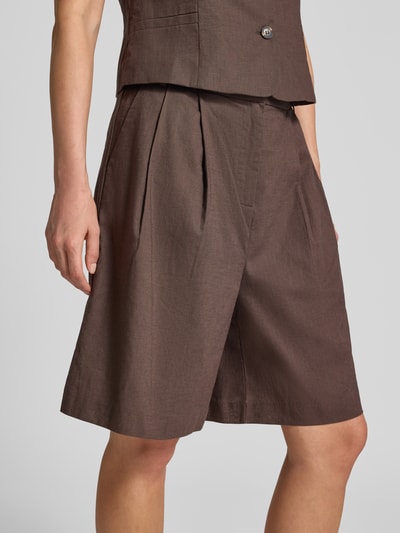 Frauenmodel trägt Bermudas aus Baumwoll-Leinen-Mix Modell 'Nika' von Neo Noir in Braun mit gelegten Falten, Regular Fit, Nahaufnahme Oberkörper. Kontext: Damen Bermudas von Neo Noir, Bundweite 39 cm, Innenbeinlänge 20 cm (Größe 36).