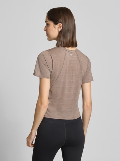 Frauenmodel trägt Cropped Fit T-Shirt mit Logo-Print von Salomon, braun, kurzer Schnitt, Rundhalsausschnitt, Ganzkörperansicht Rückansicht.