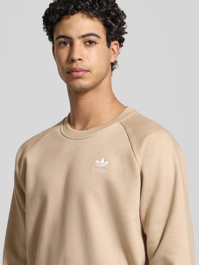 Männermodel trägt Sweatshirt mit Label-Stitching von adidas Originals aus Baumwoll-Mix, Regular-Fit, beige, Nahaufnahme Oberkörper.