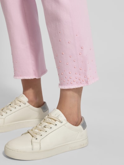 Vrouwenmodel draagt Slim Fit Jeans met fransen van Marc Cain, roze Mix van katoen en elastaan, steekzakken, franjes, detailopname onderbeen.