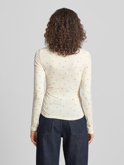 Frauenmodel trägt Longsleeve mit Viskose-Anteil von OH APRIL, Viskose-Elasthan-Mix, Körpernaher-Schnitt, U-Boot-Ausschnitt, Label-Stitching, Rückenlänge bei Größe S: 110 cm, dezentes Muster auf hellem Stoff, Ganzkörperansicht Rückansicht.