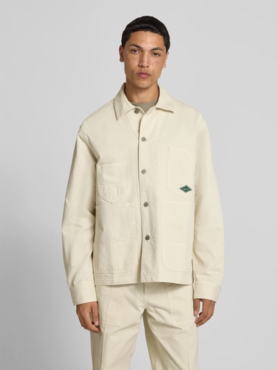 Männermodel trägt Relaxed Fit Jacke in Denim-Optik von Forét, Reine Baumwolle, Kentkragen, AufgesetzteTaschen, hellbeige, Ganzkörperansicht von vorne. Rückenlänge 74 cm, Schulterbreite 51 cm, Ärmellänge 67 cm, Größe M.
