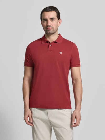 Männermodel trägt Slim Fit Poloshirt mit Logo-Stitching von MCNEAL in Rot, reine Baumwolle, Polokragen, Ganzkörperansicht von vorne.
