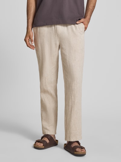 Männermodel trägt Hose aus Leinen-Baumwoll-Mix Modell 'MAXIM' von Blend, beige Farbe, entspannte Passform, elastischer Bund, Ganzkörperansicht von vorne.