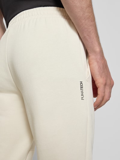 Männermodel trägt Regular Fit Sweathose mit Logo-Print Modell 'Pumatech' von PUMA PERFORMANCE, cremefarben, Baumwoll-Mix, Detailaufnahme Oberschenkel.
