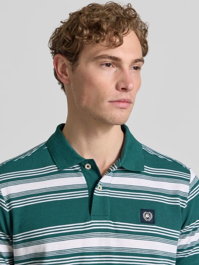 Männermodel trägt Regular Fit Poloshirt mit Label-Patch von Lerros, grün-weiß gestreift, Reine Baumwolle, Nahaufnahme Oberkörper. Rückenlänge bei Größe M: 69 cm, Polokragen, Knopfleiste.