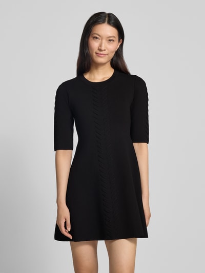 Frauenmodel trägt Minikleid aus Viskose-Mix Modell 'Abito Maglia' von Liu Jo White, körpernah, schwarz, Zierbesatz, Ganzkörperansicht von vorne.