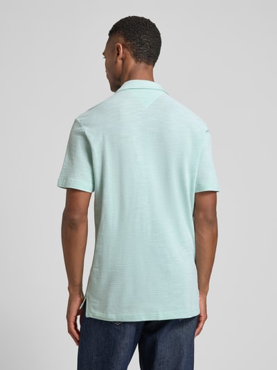 Männermodel trägt Regular Fit Poloshirt aus reiner Baumwolle von Tommy Hilfiger in melierter Optik, Ganzkörperansicht Rückansicht.