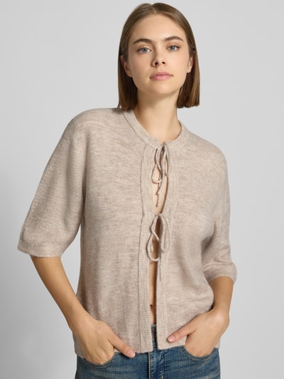 Frauenmodel trägt Regular Fit Strickjacke mit Schnürung Modell 'SIMONI' von ONLY, beige Melange-Optik, Damen Strickjacke, Nahaufnahme Oberkörper.