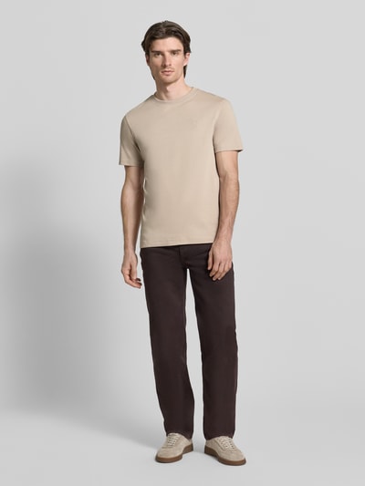 Männermodel trägt T-Shirt mit Label-Stitching Modell 'Priamo' von JOOP! Collection aus reiner Baumwolle, beige, Ganzkörperansicht von vorne.