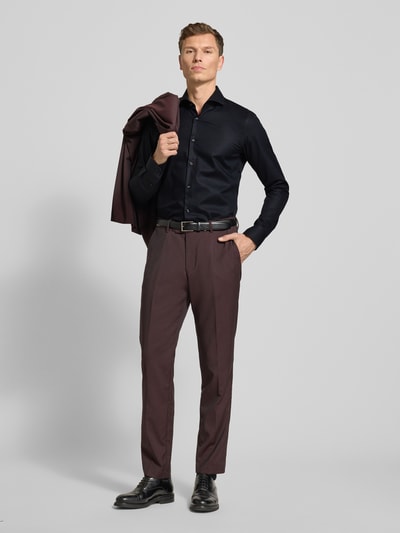 Männermodel trägt Slim Fit Businesshemd mit extra langem Arm Modell 'HANK' von BOSS in Unifarben, feines Strukturmuster, Ganzkörperansicht von vorne.