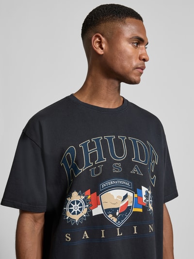 Männermodel trägt Relaxed Fit T-Shirt mit Motiv-Print von RHUDE, reine Baumwolle, Rundhalsausschnitt, schwarz, Nahaufnahme Oberkörper.