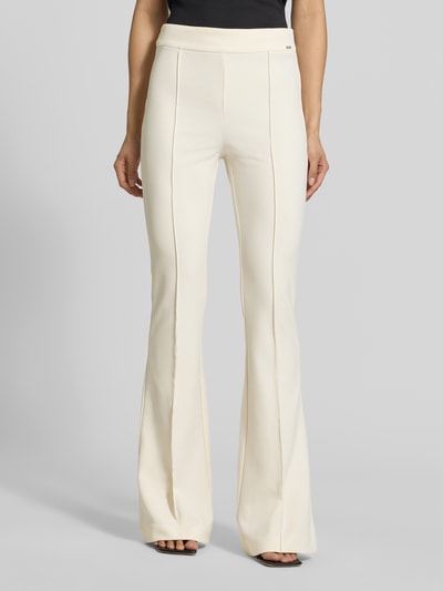 Frauenmodel trägt Flared Hose mit Längsnähten Modell 'NEW FLARED EVELINA' von GUESS in Creme mit elastischem Bund, Ganzkörperansicht von vorne.