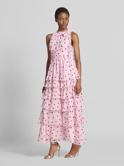 Frauenmodel trägt Abendkleid mit Rüschenbesatz Modell 'Marli' von Neo Noir in Rosa mit Punkten, tailliertem Schnitt und Zierschleife, Ganzkörperansicht von vorne.