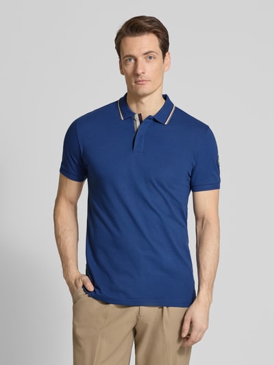 Männermodel trägt Slim Fit Poloshirt aus Baumwolle von Colmar Originals in Blau mit Polokragen, Label-Details, Ganzkörperansicht von vorne.