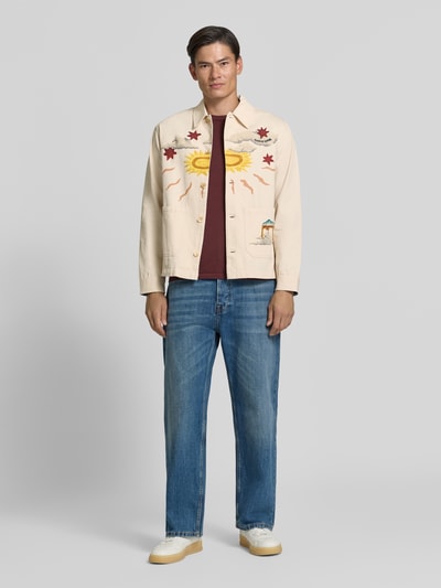 Männermodel trägt Regular Fit Overshirt mit Motiv-Prints- und -Applikationen von Scotch & Soda, beige, Jeans, Ganzkörperansicht von vorne