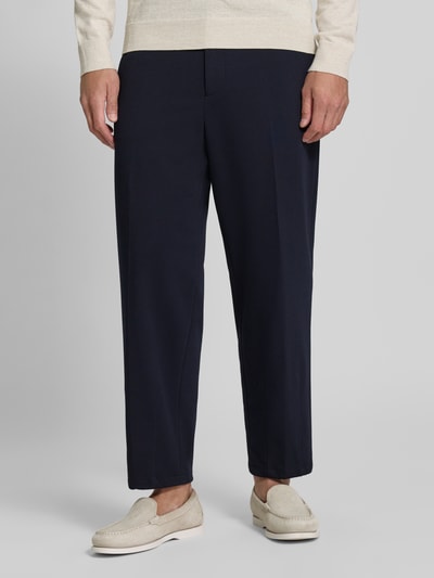 Męski model nosi spodnie materiałowe Straight Fit Stoffhose mit Viskose-Anteil Modell 'Glen' od Zuitable, ciemnogranatowe, elastyczna mieszanka materiałów z dodatkiem wiskozy, zakładki w pasie, kieszenie wpuszczane i tylne, szerokość w rozmiarze 50: 45 cm, długość wewnętrzna nogawki w rozmiarze 50: 71 cm, całkowity widok od przodu.