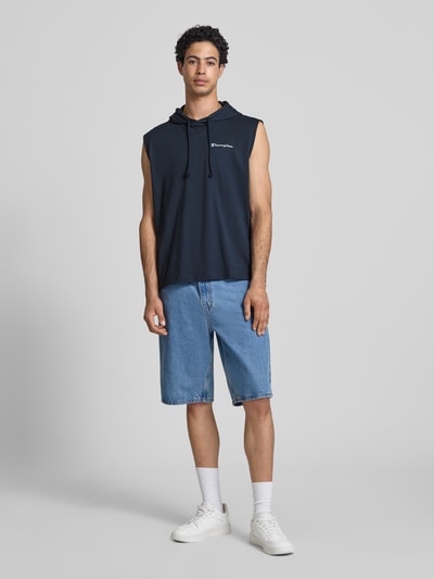 Männermodel trägt Hoodie mit Label-Stitching von CHAMPION in Dunkelblau, reine Baumwolle, Regular Fit, Ganzkörperansicht von vorne.