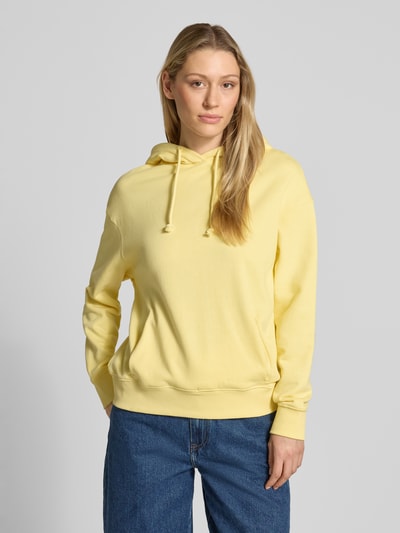 Kobiece modelka nosi Hoodie mit Logo-Stickerei Modell 'LEA' von Mustang z bawełny, luźny krój, kaptur z tunelem, wyhaftowane logo, kieszeń kangurka, prążkowane wykończenia, widok na cały przód.