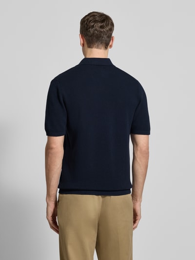Männermodel trägt Regular Fit Poloshirt mit gerippten Abschlüssen von MCNEAL in Dunkelblau zu beiger Hose, Baumwolle, Ganzkörperansicht Rückansicht.