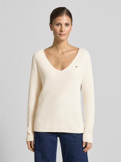 Vrouwenmodel draagt Regular Fit Gebreide pullover uit puur katoen van Tommy Hilfiger, effen look, gestikt logo, V-hals, lange raglanmouwen, ribtricot, voorkant, ganzekörperaanzicht.