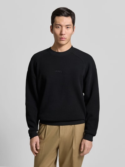 Männermodel trägt schwarzes Regular Fit Sweatshirt aus reiner Baumwolle Modell 'DAFFLYN' von HUGO, Strukturmuster, Ganzkörperansicht von vorne.