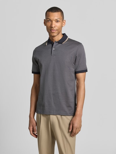 Männermodel trägt Regular Fit Poloshirt mit Polokragen und kurzer Knopfleiste von bugatti in Reine Baumwolle, Label-Detail, Ganzkörperansicht von vorne. Rückenlänge bei Größe M: 70 cm, dezentes Muster in Dunkelgrau, beige Hose.