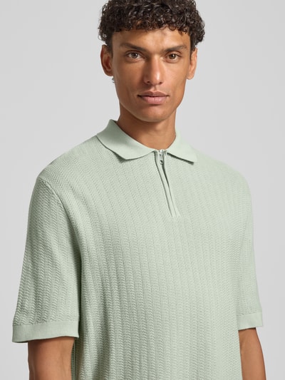 Männermodel trägt Regular Fit Poloshirt aus reiner Bio-Baumwolle Modell 'CRAN' von SELECTED HOMME in Strickoptik, Nahaufnahme Oberkörper.