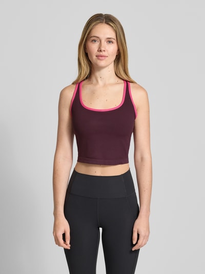 Frauenmodel trägt Cropped Top mit integriertem Bustier von Fabletics aus Elastischer-Material-Mix in Dunkellila mit Rückenausschnitt, Ganzkörperansicht von vorne. Rückenlänge bei Größe L: 13 cm.