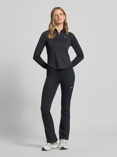 Frauenmodel trägt Flared Cut Leggings mit Logo von NIKE TRAINING, Material-Mix mit Stretch-Anteil, elastischer Bund, Schwarz, Ganzkörperansicht von vorne.