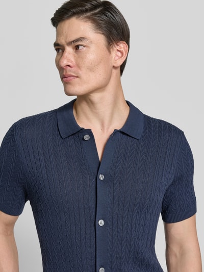 Männermodel trägt Poloshirt in Strick-Optik Modell 'Tristao' von JOOP! Collection, reine Baumwolle, Slim-Fit, Nahaufnahme Oberkörper.