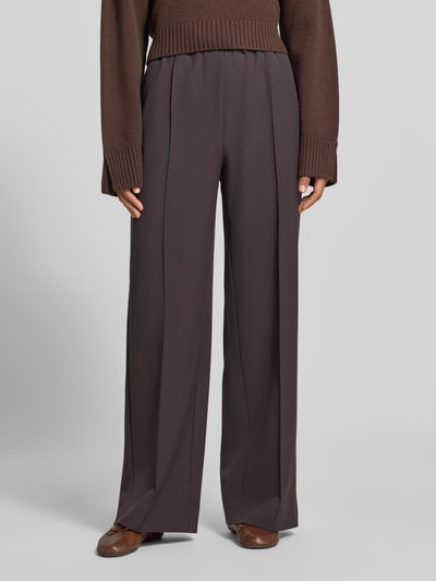 Frauenmodel trägt Wide Fit Sweatpants mit Viskose-Anteil von MYON in Dunkelbraun, sichtbare Zierfalten, elastischer Bund, Ganzkörperansicht von vorne.