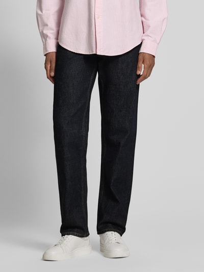 Männermodel trägt Straight Fit Jeans aus reiner Baumwolle Modell 'DOVER' von Tommy Hilfiger in dunkler Denim-Optik, 5-Pocket-Design, Kontrastnähte, Label Patch, Knopf und verdeckter Reißverschluss, Ganzkörperansicht von vorne.