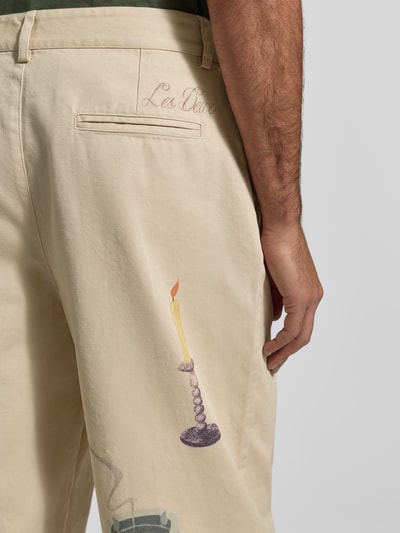 Männermodel trägt Stoffhose mit Motiv-Prints Modell 'Romeo' von Les Deux in Beige, Gesäßtaschen, Detailaufnahme Rückansicht.