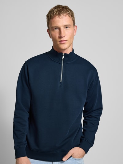 Männermodel trägt Regular Fit Troyer aus reiner Baumwolle von Marc O'Polo Denim in dunklem Blau, Sweat-Optik, Nahaufnahme Oberkörper.