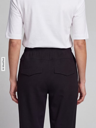 Männermodel trägt Barrel Leg Hose mit angedeuteten Taschen Modell 'Rachell' von Stehmann, jednokolorowy, krój barrel fit, średni stan, elastyczny pas, wpuszczane kieszenie, wykończenie materiału: dzianina dresowa, Ganzkörperansicht Rückansicht, KI-modifiziertes Bild