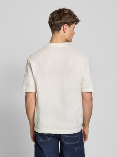 Männermodel trägt Relaxed Fit Poloshirt Modell 'FERDINAND' von Redefined Rebel aus Reine Baumwolle, Strickshirt mit Knopfleiste, Rückenlänge 70 cm bei Größe M, cremefarbene Struktur, Ganzkörperansicht Rückansicht.