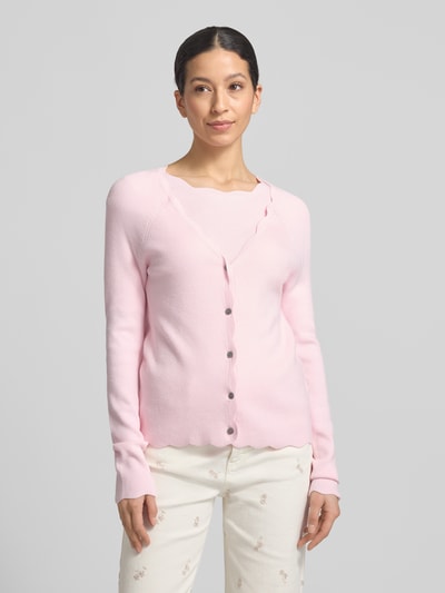 Frauenmodel trägt Strickcardigan aus Viskose-Mix von Christian Berg Woman, tailliert, Rüschen, Knopfleiste, V-Ausschnitt, Ganzkörperansicht von vorne.