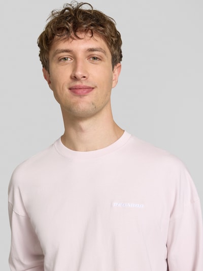 Männermodel trägt Oversized Sweatshirt mit Logo-Stitching Modell 'Rusk' von Pegador aus Reine Baumwolle in zartem Rosa, Nahaufnahme Oberkörper.