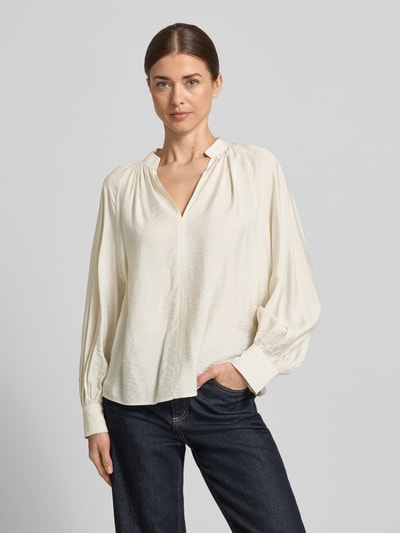 Frauenmodel trägt Bluse aus Viskose-Mix mit Serafino-Ausschnitt von Christian Berg Woman in Creme, lockere Passform, Sportmanschetten, Nahaufnahme Oberkörper.