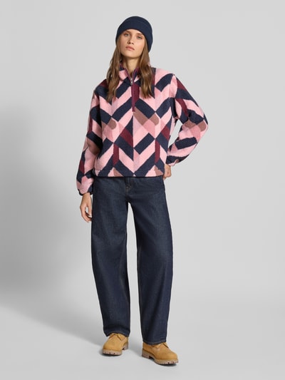 Kobiece model prezentuje Regular Fit Troyer mit Stehkragen Modell 'NEW' od ONLY, różowe, granatowe i beżowe geometryczne wzory, faktura miękkiego materiału, dżinsy, Ganzkörperansicht von vorne, troyer damski od ONLY
